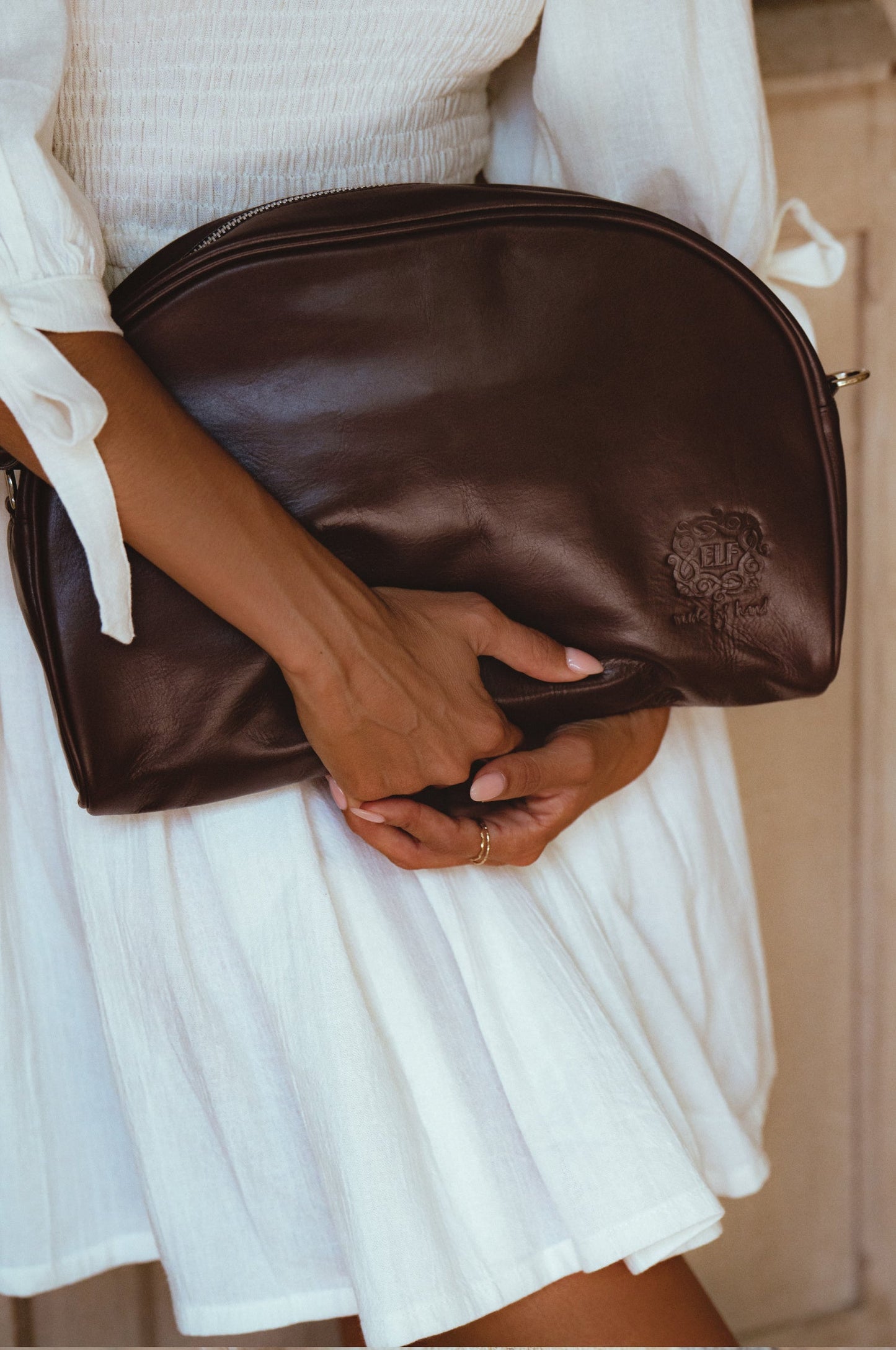 Model holding a Sabine Leather Handbag, showcasing its high-quality brown leather and stylish design.