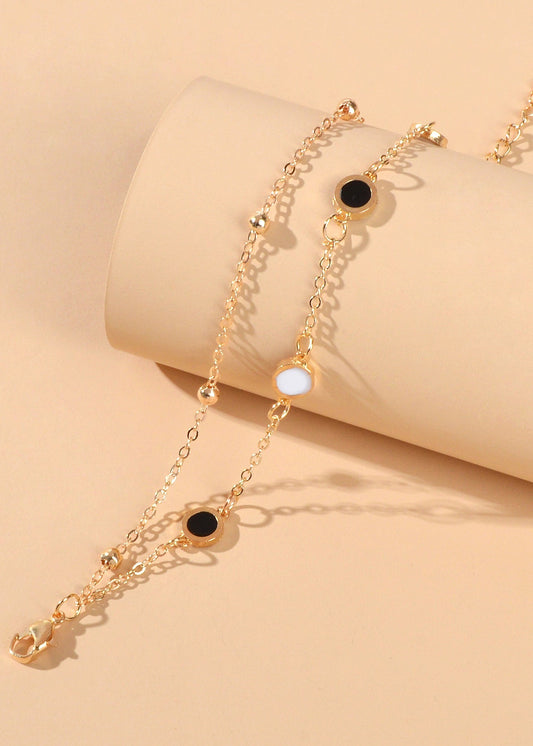 Round Disc Double Layer Bracelet featuring gold chains and black and white disc accents.