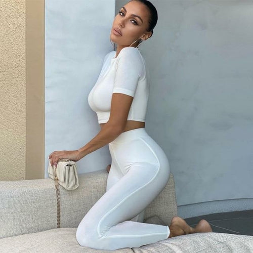 2 Piece Set Long Sleeve Solid Crop Top and Leggings modeled in white outfit on a couch.