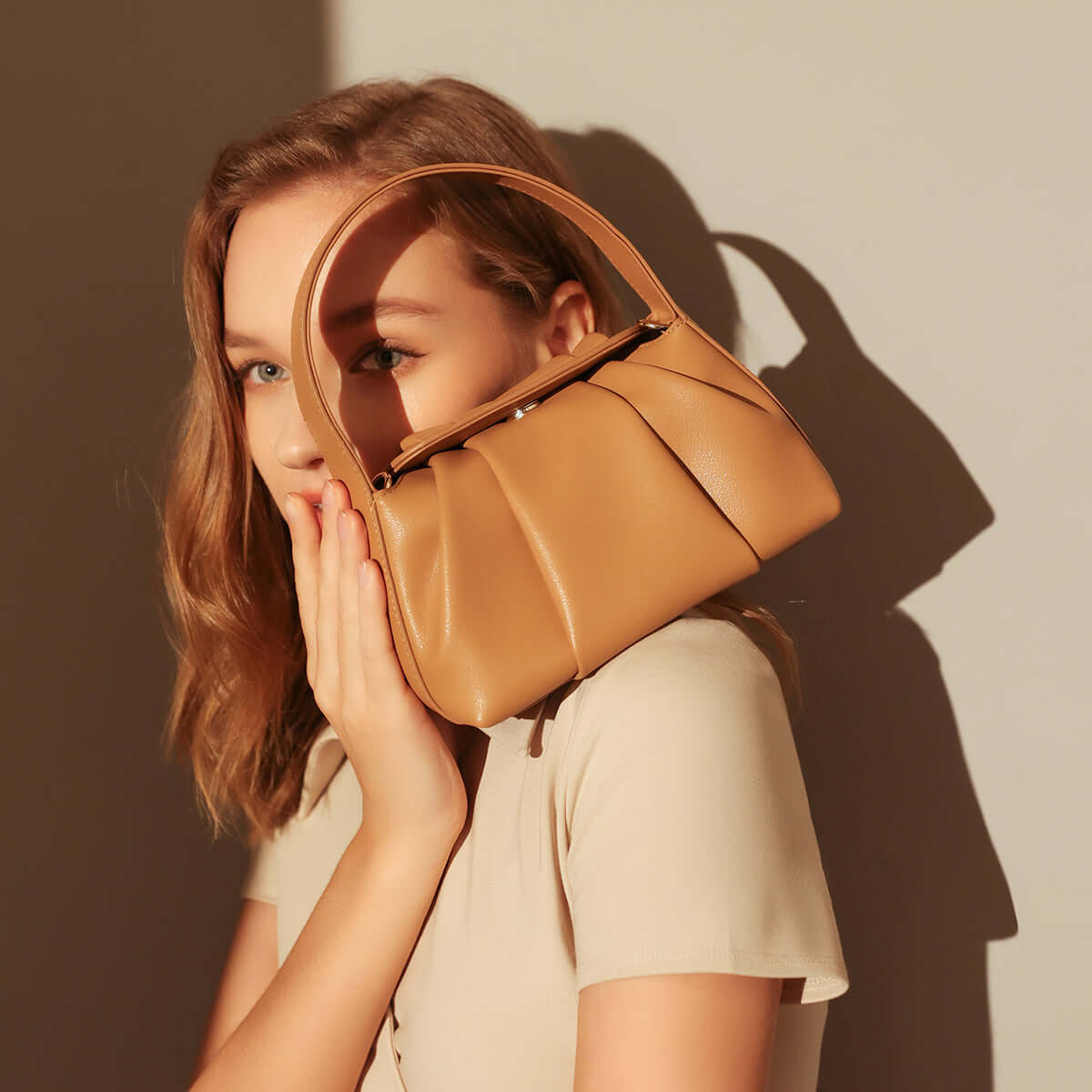 Ruched Leather Handbag held by a model, showcasing its elegant pleats and natural silhouette.